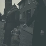 Straßenszene in Bochum-Riemke: Kind mit Mutter und Nonne vor Kirche, nachgestellte Erinnerung aus den 1970er Jahren.