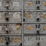 Ausschnitt eines alten Schubladenschranks mit mehreren nummerierten Fächern – Symbol für das Sortieren von Menschen, Meinungen und Kategorien.