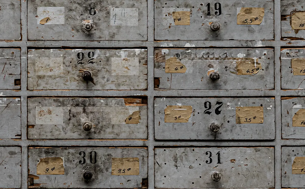 Ausschnitt eines alten Schubladenschranks mit mehreren nummerierten Fächern – Symbol für das Sortieren von Menschen, Meinungen und Kategorien.
