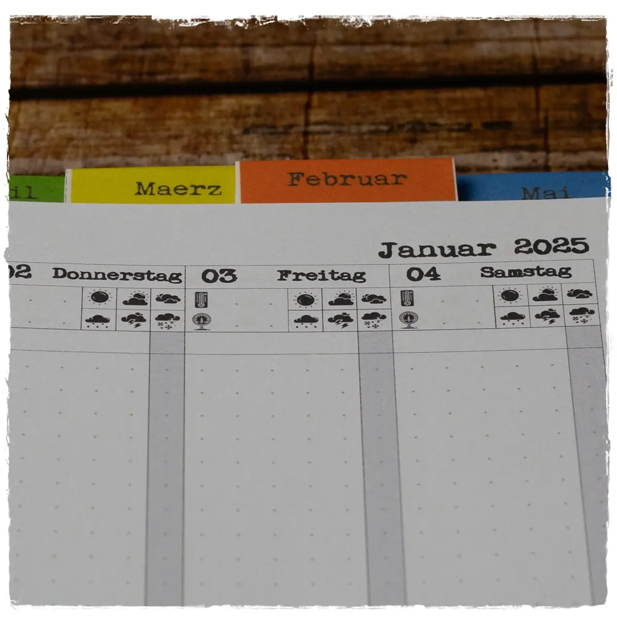 Blick auf Monatsplaner mit eingeklebten Tabs – bunte Karteireiter für Januar bis Mai sichtbar von oben.